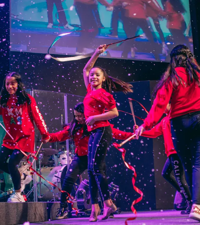 Bailarinas con ropa roja haciendo una coreografía con cintas sobre un escenario